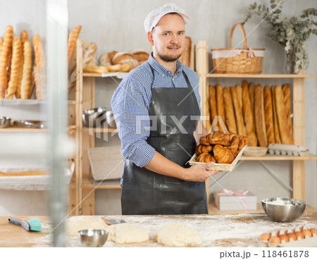 Male baker holds basket with finished products, shows many different croissants 118461878