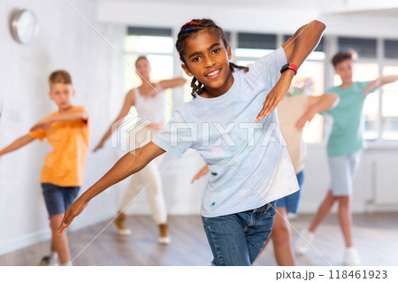 Positive juvenile boy engaged in Hip-hop dance in training room with children's group Positive juvenile boy engaged in Hip-hop dance in training room with children's group 118461923