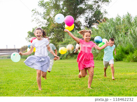 Boys and girls with balloons running thruogh field 118462232