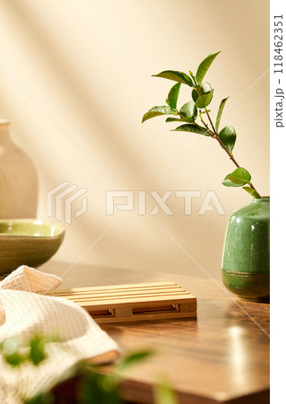 warm minimalist spa room setting with product display space on pallet placed on wooden table next to emerald vase and green ceramic cup. Product advertising photo. warm minimalist spa room setting with product display space on pallet placed on wooden table next to emerald vase and green ceramic cup. Product advertising photo. 118462351