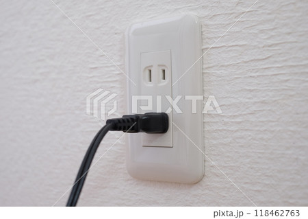 漆喰の壁につけられたコンセントとプラグ 118462763
