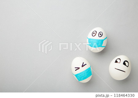 White Easter eggs in protective medical mask and one egg without mask on grey background. Easter on quarantine concept with place for text. Stop VIRUS COVID-19. Copy space. Egg in mask. 118464330