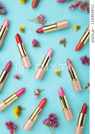 Lipstick with beautiful flowers on blue background with copy space. Vertical photo Lipstick with beautiful flowers on blue background with copy space. Vertical photo 118464652