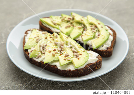 Avocado sandwich on dark rye bread made with fresh sliced avocados on grey background. Avocado sandwich on dark rye bread made with fresh sliced avocados on grey background. 118464895