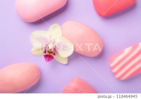 Different pink soaps with flowers. A lot of solid soap for hygiene and cleanliness on a purple background. Different pink soaps with flowers. A lot of solid soap for hygiene and cleanliness on a purple background. 118464945