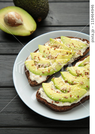 Avocado sandwich on dark rye bread made with fresh sliced avocados on dark background. Avocado sandwich on dark rye bread made with fresh sliced avocados on dark background. 118464946