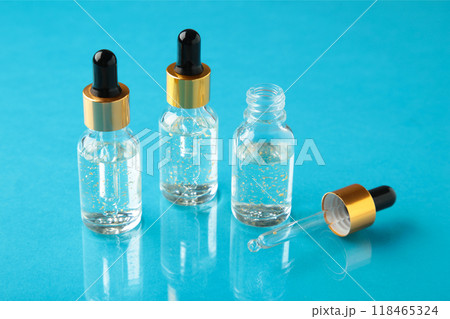 A glass bottles with a pipette with oil, serum on blue background with copy space. Flatlay A glass bottles with a pipette with oil, serum on blue background with copy space. Flatlay 118465324