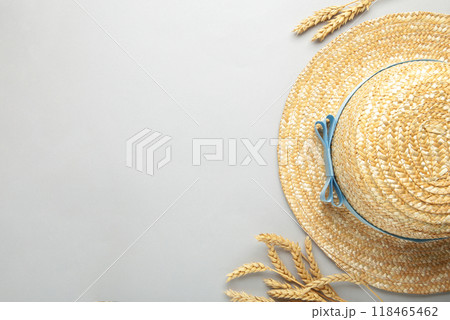 Top view of straw beach hat with blue ribbon and spikelets on grey background. Top view of straw beach hat with blue ribbon and spikelets on grey background. 118465462