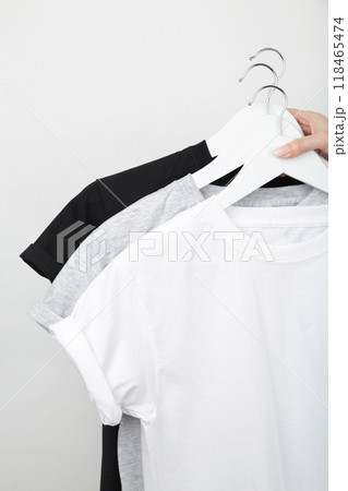 Young girl holding a set of white. black and grey t-shirts. Top view. Young girl holding a set of white. black and grey t-shirts. Top view. 118465474