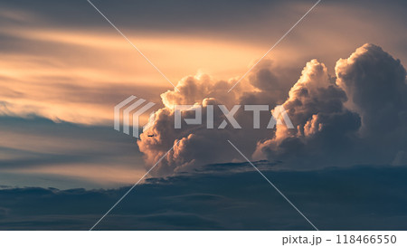 夕焼けに染まる積乱雲の脇を飛行する航空機 118466550