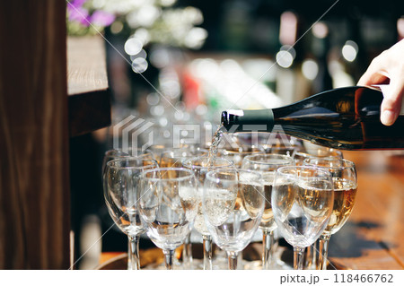 A waiter pours wine into glasses at an outdoor buffet. 118466762