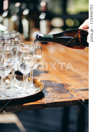 A waiter pours wine into glasses at an outdoor buffet. 118466763