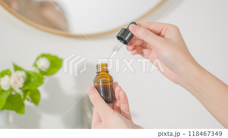 Skincare products promotional photo in bathroom concept, was taken from front view with hand model. An amber serum bottle without label is opened, prepare for skincare routine 118467349