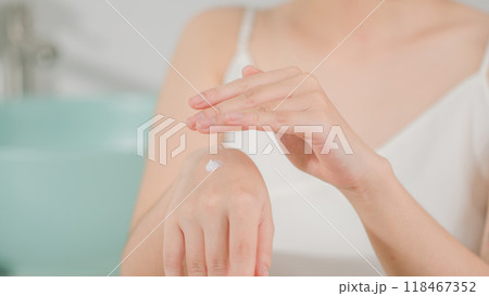 Close up shot at scene a female wears white dress in bathroom, prepare to spread white moisturizer cream on the back of hand. Frontal shot, empty space for adding text Close up shot at scene a female wears white dress in bathroom, prepare to spread white moisturizer cream on the back of hand. Frontal shot, empty space for adding text 118467352