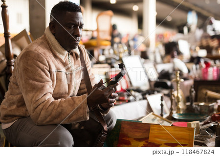 Man chooses antiques at a flea market Man chooses antiques at a flea market 118467824