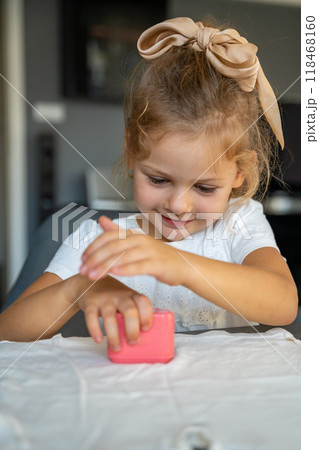 Little girl with a stamp with a name for signing children's things. Identification of personal clothing.  118468160