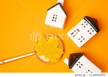 Magnifying glass with yellow leaf and miniature houses. Autumn real estate concept. House searching or appraisal. Property valuation. Search for housing, apartments. Falling season Magnifying glass with yellow leaf and miniature houses. Autumn real estate concept. House searching or appraisal. Property valuation. Search for housing, apartments. Falling season 118469040