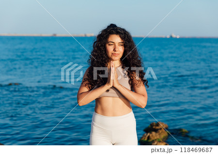 Athletic woman doing gymnastics yoga asana by the sea 118469687