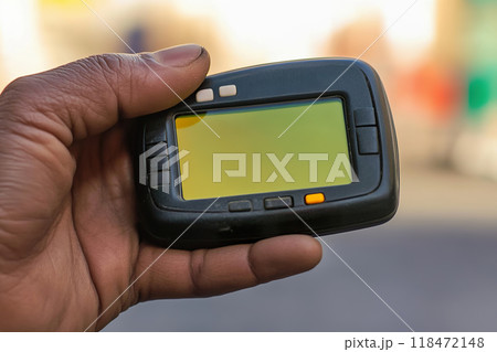 male hand holds pager while a blurred Middle Eastern street in the background male hand holds pager while a blurred Middle Eastern street in the background 118472148