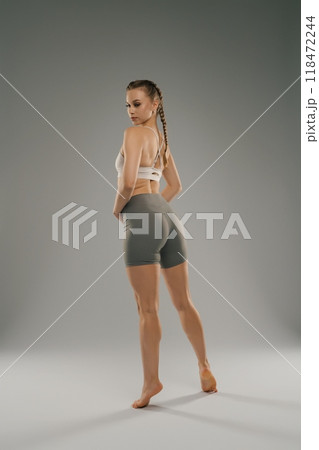 Young woman posing in workout attire against a neutral background 118472244