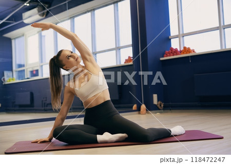 Woman practicing yoga stretches in a fitness studio with vibrant decor 118472247