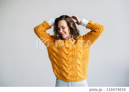 A woman in a yellow sweater is smiling and posing for the camera 118474658