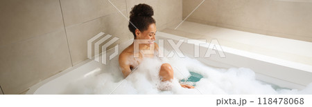 Woman enjoying a foamfilled bath in a bathtub, relaxing in the bathroom 118478068
