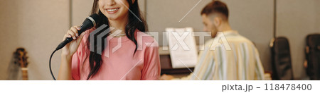 Young Woman Singing into Microphone in Music Studio 118478400