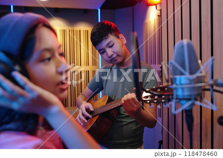 Singing and Playing Guitar in Professional Recording Studio 118478460