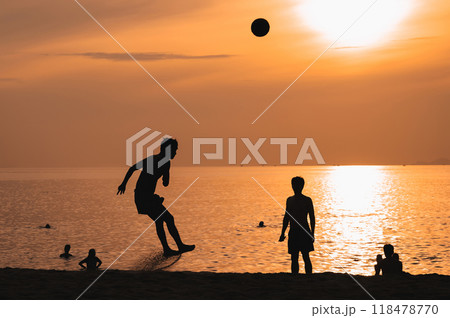 Silhouettes of Asian men playing beach soccer on beach by sea at sunrise Silhouettes of Asian men playing beach soccer on beach by sea at sunrise 118478770