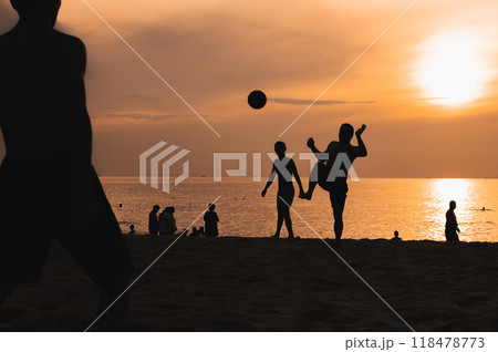 Silhouettes of a group of Asian men playing traditional beach football on beach by the sea at sunset 118478773