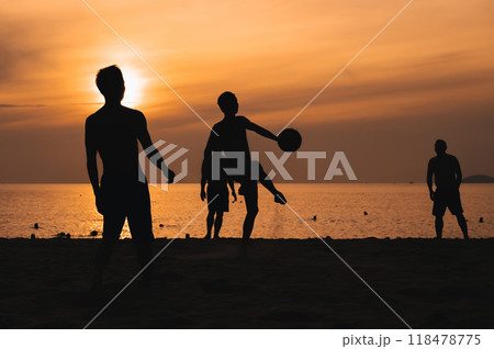 Silhouettes of a group of Asian men playing traditional beach soccer on a beach by sea at sunset Silhouettes of a group of Asian men playing traditional beach soccer on a beach by sea at sunset 118478775