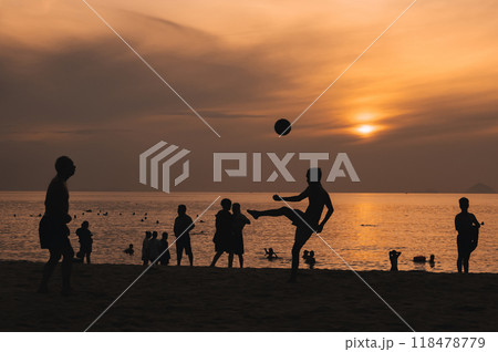 Silhouettes of a group of Asian men playing traditional beach soccer on a beach by sea at sunset 118478779