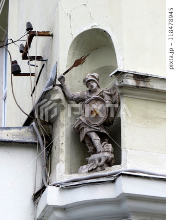 Niche stone statue of angel Saint George flaming sword of victorious dragon, Cracked plaster wall 118478945