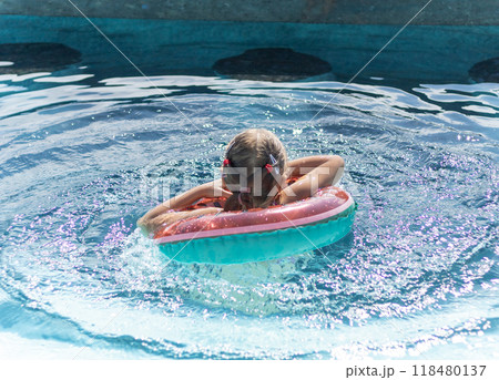 little girl with inflatable ring swims in swimming pool little girl with inflatable ring swims in swimming pool 118480137