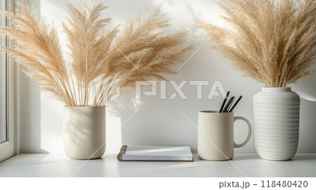 Decorative dried flowers in neutral vases arranged on a minimalist white tabletop 118480420