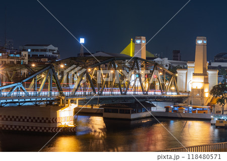 illuminated bridge at night reflects beautifully on water, showcasing vibrant cityscape. scene captures essence of urban life and architectural design 118480571