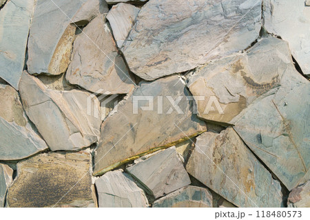 Natural stone wall texture features irregularly shaped slate pieces in earthy tones. unique patterns and colors create rustic and organic feel, perfect for various design applications 118480573