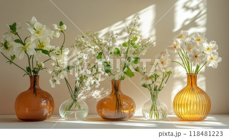 Elegant display of vases with flowers and sunlight streaming through a window in a bright room 118481223