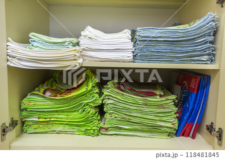 Interior of white plastic cabinet or clothing wardrobe with open doors with stacked pile of clean colorful linen. Household and order, furniture design concept. 118481845