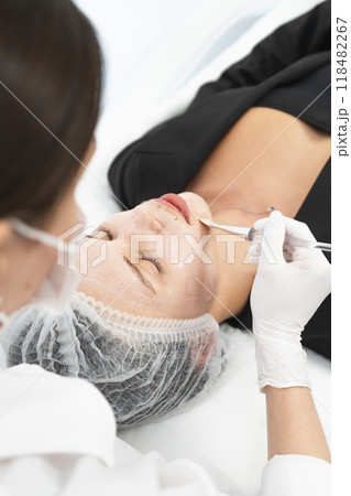 The young female client of cosmetic salon having a cleansing facial mask 118482267