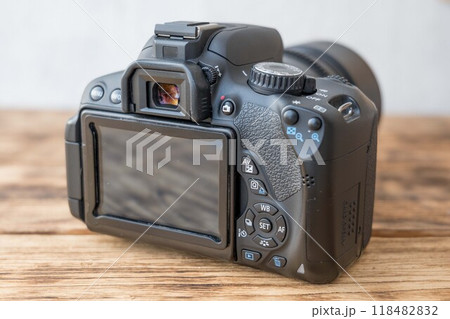 Modern dslr camera sitting on wooden table back side showing Modern dslr camera sitting on wooden table back side showing 118482832