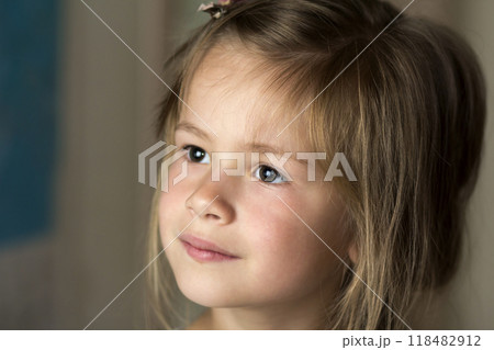 Portrait of little pretty young child girl with gray eyes and clip in scattered fine blond hair looking dreamily in distance on blurred sunny background. Beauty, dreams and innocence of childhood. Portrait of little pretty young child girl with gray eyes and clip in scattered fine blond hair looking dreamily in distance on blurred sunny background. Beauty, dreams and innocence of childhood. 118482912