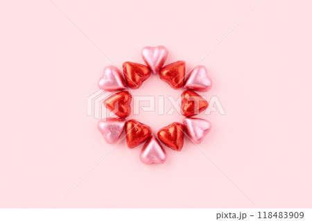 A circle made of heart shaped chocolate candies on pink background 118483909