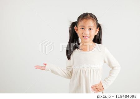Asian happy portrait cute young girl smile presenting product holding something on palm away side, studio shot isolated on white background with copy space, kindergarten child show hand gesture 118484098