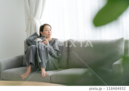 ソファーに座ってスマホを使う女性 ソファーに座ってスマホを使う女性 118484932