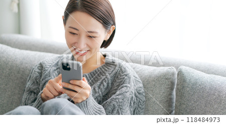 ソファーに座ってスマホを使う女性（バナーサイズ） 118484973
