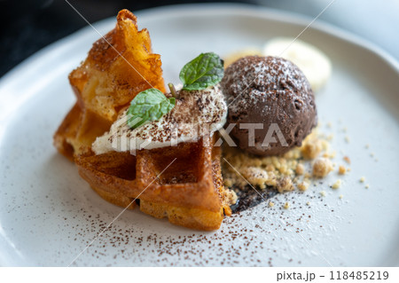 Waffle with chocolate ice cream served with cookie crumble, whipped cream and banana on plate Waffle with chocolate ice cream served with cookie crumble, whipped cream and banana on plate 118485219