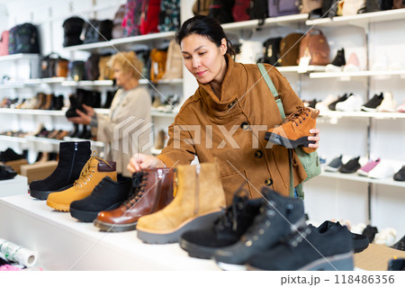 Asian woman chooses Timberland style autumn boots Asian woman chooses Timberland style autumn boots 118486356