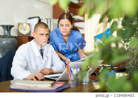 Doctor gives task to assistant at office 118486481